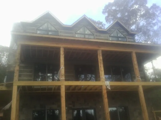 Dormers and porch framing on a large log home under construction — Roof Coating work by our crew in Satsuma