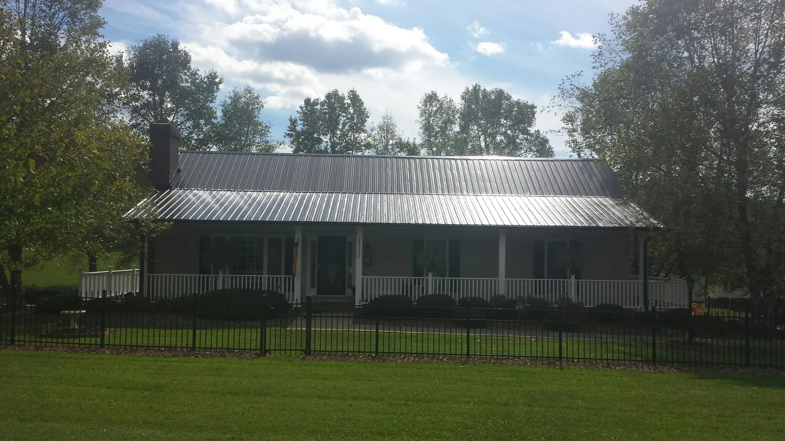Gray metal roof on a brick ranch with a full width front porch — Gutter Guard Installation work by our crew in Satsuma