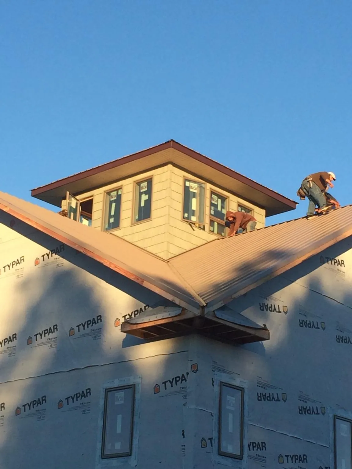 Roofers working around a rooftop cupola on a new metal roof at sunset — Roof Waterproofing in Satsuma by Roofing Brothers